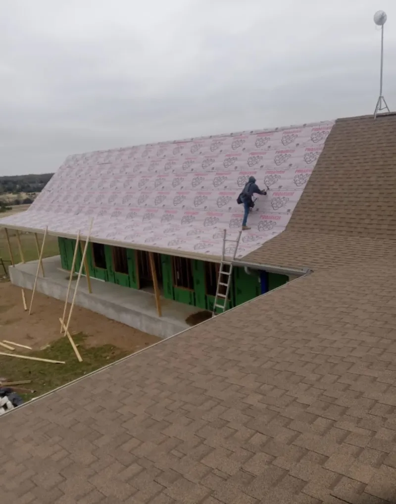 Worker preparing underlayment for a metal roof installation in Alvarado